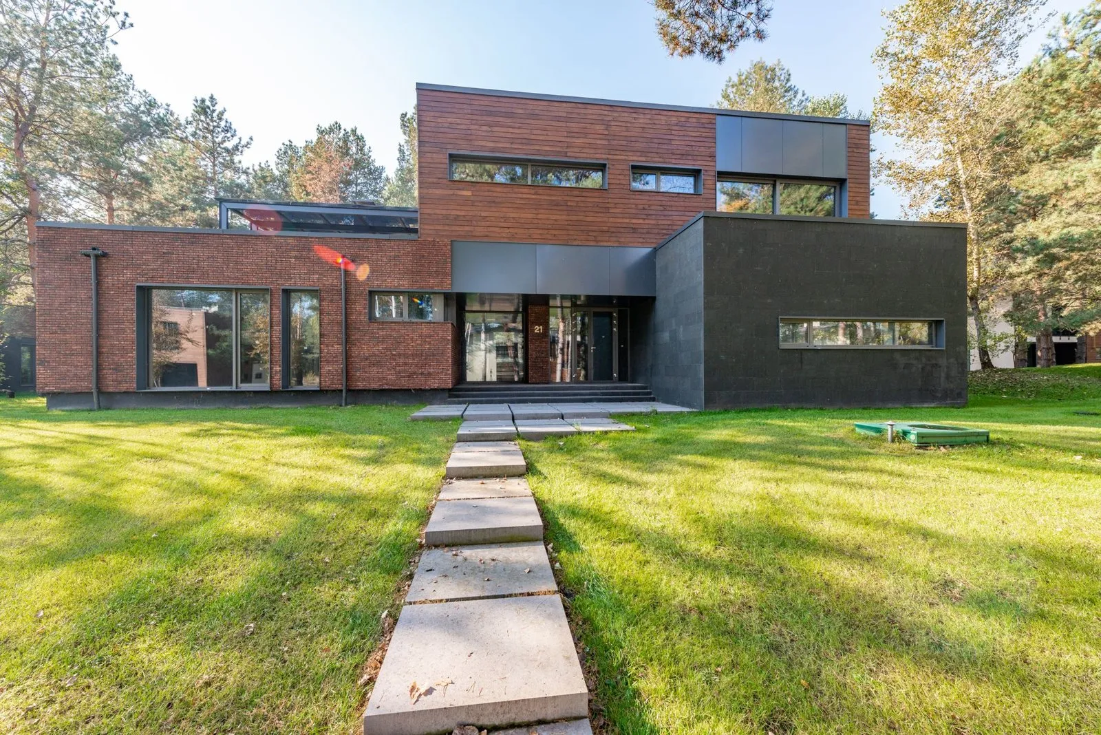 Front of the house, brick on the left, dark stone block on the right, a stepping-stone path across the lawn.